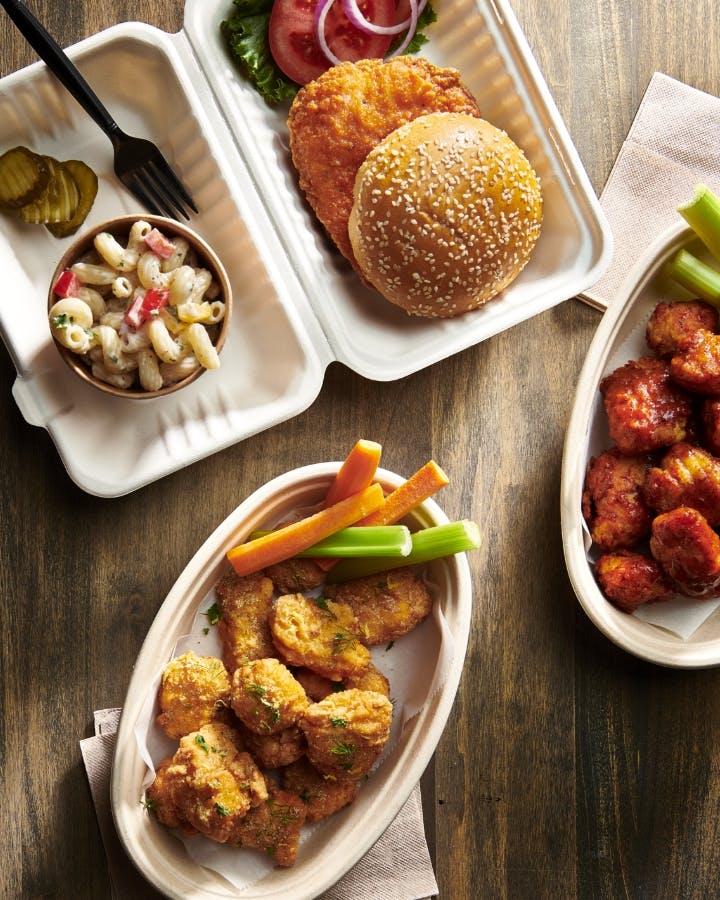 Top down view of a chicken sandwich, chicken nuggets and sides on a wood table