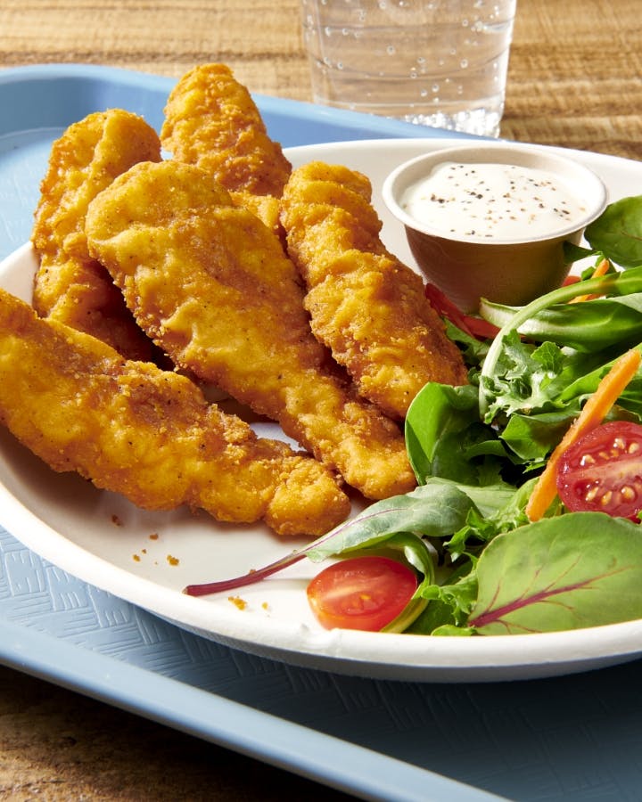 Chicken strips with side salad on a lunch tray
